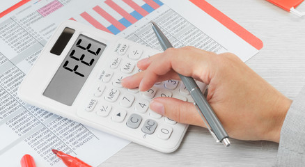 Fee text on a calculator with financial data paperwork on the desk. Business and finance FEE and regular subscription or payments concept