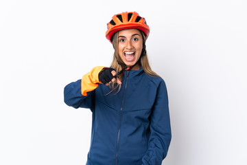 Young hispanic cyclist woman isolated on white background surprised and pointing front