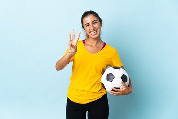 Young hispanic football player woman over isolated on blue background happy and counting three with fingers