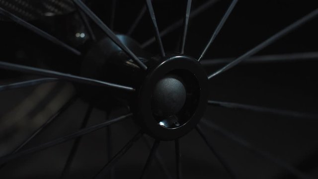 Close up spinning spokes and wheel hub of black wheelchair. Motion control system. Camera moving up
