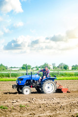 The farmer drives a tractor with a milling unit equipment. Loosening land cultivation Use of agricultural machinery to speed up work. Farming. Plowing field. The stage of preparing soil for planting.