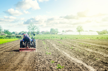 Farmer on a tractor loosens soil with milling machine. First stage of preparing soil for planting....