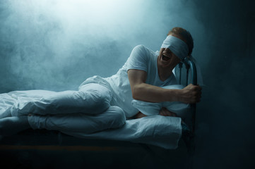 Blindfolded crazy man sitting in bed, psychedelic