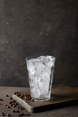 Empty glass with ice on dark background with coffe beans.Preparinf ice coffee concept