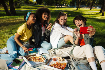 Image of student girls taking selfie on mobile phone and eating pizza