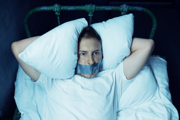 Psycho man with taped mouth lying in bed