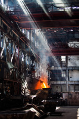 Metallurgy factory workshop. Melting of metal. Red fire, liquid metal in bucket, white smoke or steam. Taraz city. Kazakhstan.