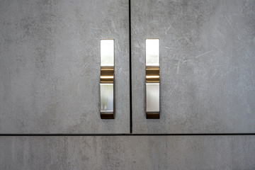 Conceptual photo of the doors of a modern gray wardrobe with chrome handles. High quality photo