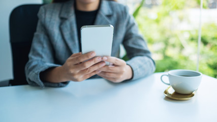 Closeup image of a businesswoman holding and using mobile phone in office