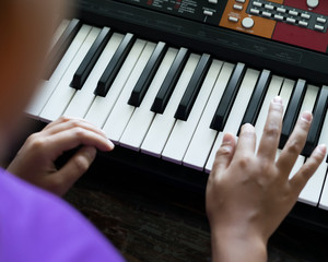 Hands of kid on piano keyboard. Playing and practising at home.