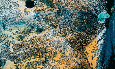 Colorful acrylic ink. Marble texture. Blue yellow fleck grain on black fluid with streak effect. Mineral stone pattern art background. Luxury rock abstract design.
