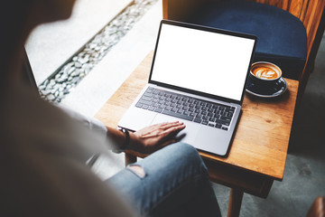 Mockup image of a businesswoman using and touching on laptop touchpad with blank white desktop screen in cafe