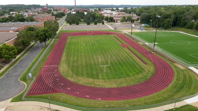 Rotating aerial view of well maintained and mowed soccer field with running track at University of Wisconsin&ndash;Stout  in Menomonie, Wisconsin.