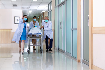Team medical doctor pushing stretcher gurney bed corridor with female patient in hospital. Health...