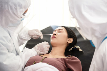 Medical  taking test swab for corona virus sample from potentially infected patient women.  Doctor suits and surgical face mask for protect Coronavirus