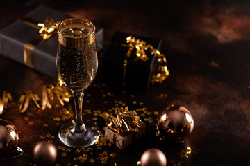 Christmas champagne, gas bubbles, confetti and blurry lights on a dark background