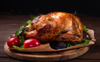 Fried chicken with spices, herbs and vegetables on a wooden table. Black background.