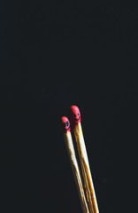 Couple of matches burning together with heat flame isolated on a black background.