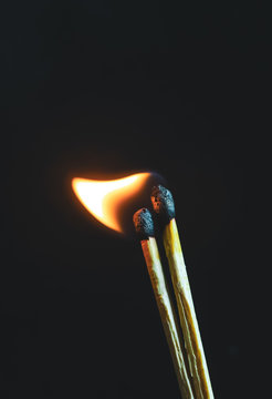 Couple of matches burning together with heat flame isolated on a black background.