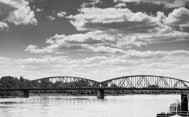 Black and white vintage photography road bridge over Vistula River in Torun (Pilsudski Bridge), Poland. Heavy rusty steel old industrial vehicle overpass. Landscape city view from boulevard.