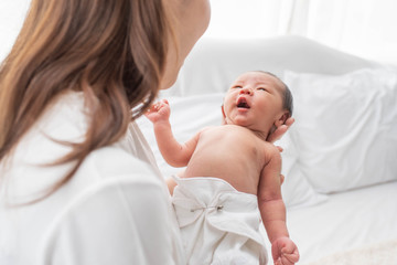 Pretty woman holding a newborn baby in her arms. happy loving family. mother playing with her baby in the bedroom.