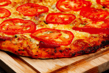 delicious fragrant hot pizza on a wooden cutting board on a wooden black table