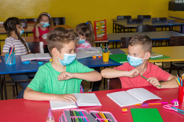 Protection during the pandemic. Two little boys  with medical mask.Greetings at school