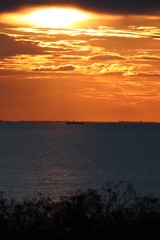 Fototapeta premium Hunstanton beach sun set over the sea ,glowing deep orange ball of fire 