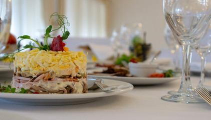 Beautiful table setting in light colors with dishes and assorted food on a table with a white tablecloth for a party, wedding or other special event. Restaurant business and service industry concept.