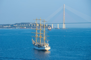 Sailing ship Hope against the sea and the Russian bridge.