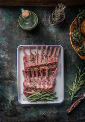 Raw lamb ribs with herbs and seasonings on a dark rustic kitchen background. Seasonings and spices...