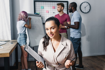 Selective focus of businesswoman holding pen and clipboard in white office