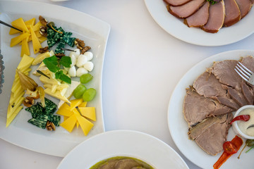 Table setting in light colors with dishes and plate with different cheeses on a table with white tablecloth for party, wedding or other special event. Restaurant business and service industry