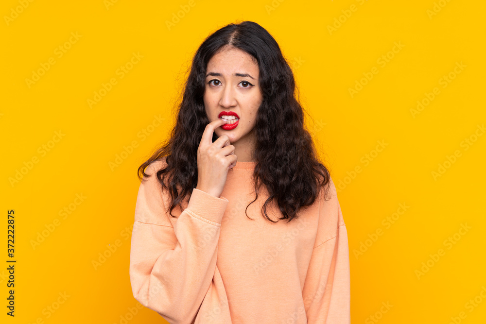 Wall mural Spanish Chinese woman over isolated yellow background nervous and scared