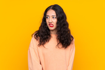 Spanish Chinese woman over isolated yellow background with confuse face expression