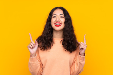 Obraz premium Spanish Chinese woman over isolated yellow background pointing up a great idea