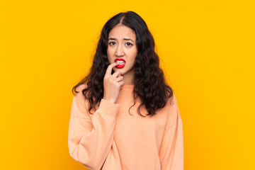 Spanish Chinese woman over isolated yellow background nervous and scared