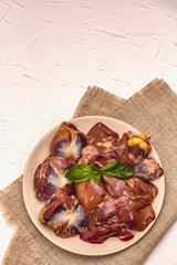 Fresh raw chicken offal: heart, liver, stomach with dry spices, sea salt, chili pepper on white putty background