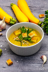 Yellow zucchini cream soup. Healthy vegan (vegetarian) food, crispy toast, sunflower seeds, whole ripe fruits, fresh greens