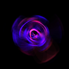 Spinning rays of light isolated on black background. Graphic 2D illustration of glowing colorful light particles in circular motion.