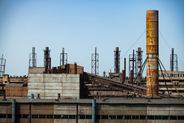 Abandoned soviet metallurgy plant (factory) buildings and rusted chimneys on the blue sky. Abstract...