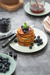 Pancakes stack with blueberries, healthy breakfast food, dark background.