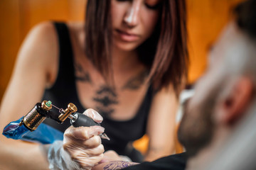 Tattoo Artist Tattooing Man’s Arm in Studio