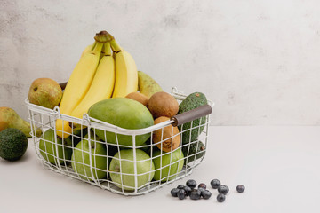 Fresh ripe fruits - green apples, green pears, bananas, kiwi and blueberies. In metal vintage basket.