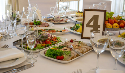 beautiful table setting in light colors with dishes and assorted food on a table with a white tablecloth for a party, wedding or other special event. Restaurant business and service industry concept. 