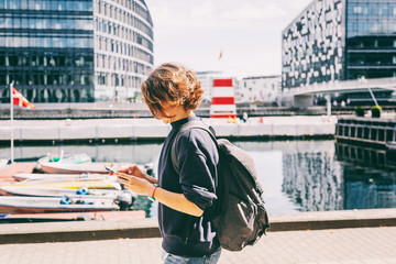 Young puppy with a mobile phone walking in front of a canal in Copenhagen in city center, Denmark. Urban Lifestal - obrazy, fototapety, plakaty