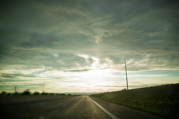 Ein Auto auf einer einsamen Autobahn im Sonnenuntergang gegen das Licht