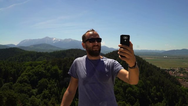 Young, happy man taking selfie photo in mountains