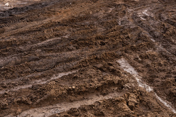 Texture of a dirty bad dirt road dirt road with puddles and clay drying mud with cracks and ruts....