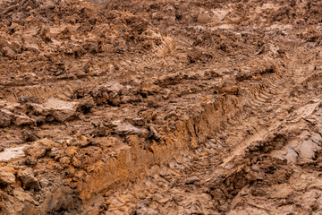 Texture of a dirty bad dirt road dirt road with puddles and clay drying mud with cracks and ruts. Off-road. The background.